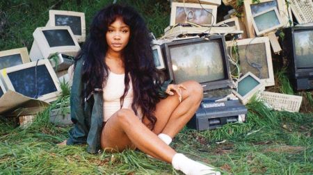 sza sitting on grass with broken old TVs and computers 